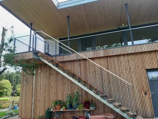 Geländer Holzhaus mit Terrasse und Treppe, bepflanzt mit Blumen und Pflanzen.