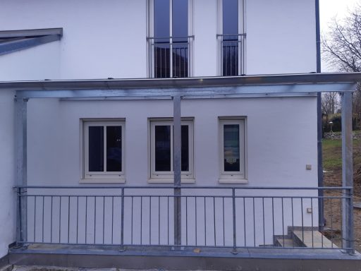 Vordach und Geländer Häuserfassade mit drei Fenstern und überdachtem Eingangsbereich.