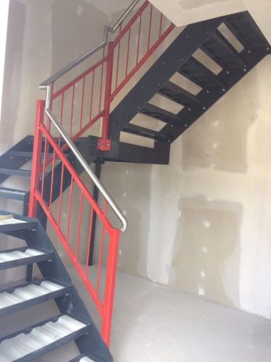 Eisentreppe mit Geländer Schwarze Metalltreppe mit roten Geländern in einem unfertigen Raum.