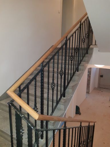 Geländer Treppenhaus mit metallischem Geländer und Holzhandlauf, beige Wände und Bodenfliesen.