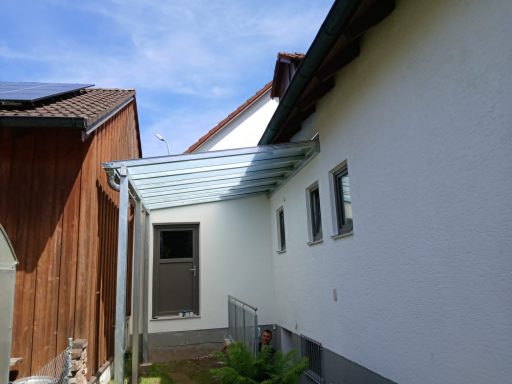 Vordach Blick auf ein Haus mit überdachtem Anbau und klarem Himmel im Hintergrund.