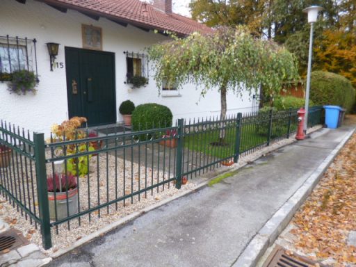 Zaun Ein weißes Haus mit grünem Zaun, Garten und einem Baum, umgeben von herbstlichen Blättern.